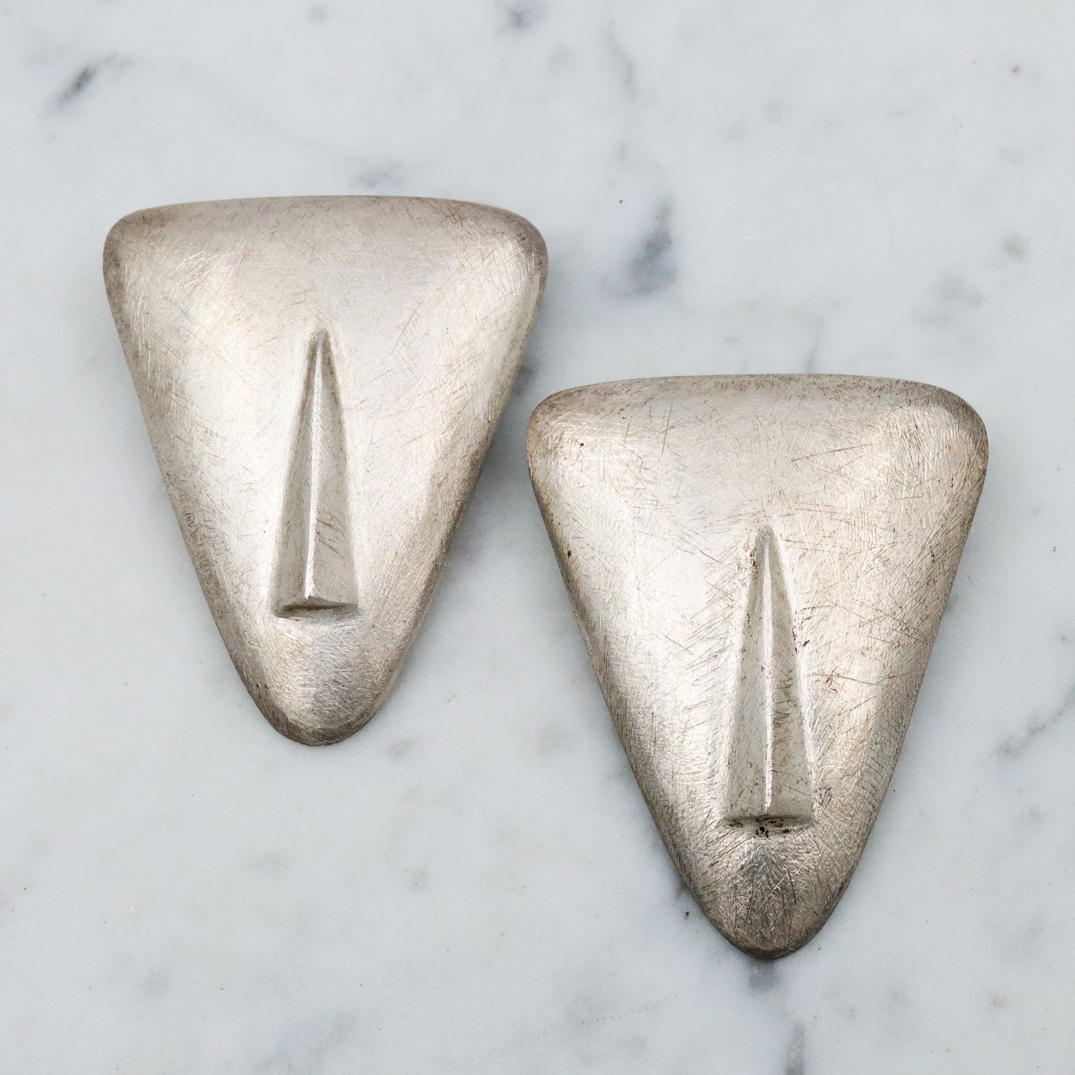 1987 pair of brushed sterling mask brooches by Modernist artist Elizabeth Earle