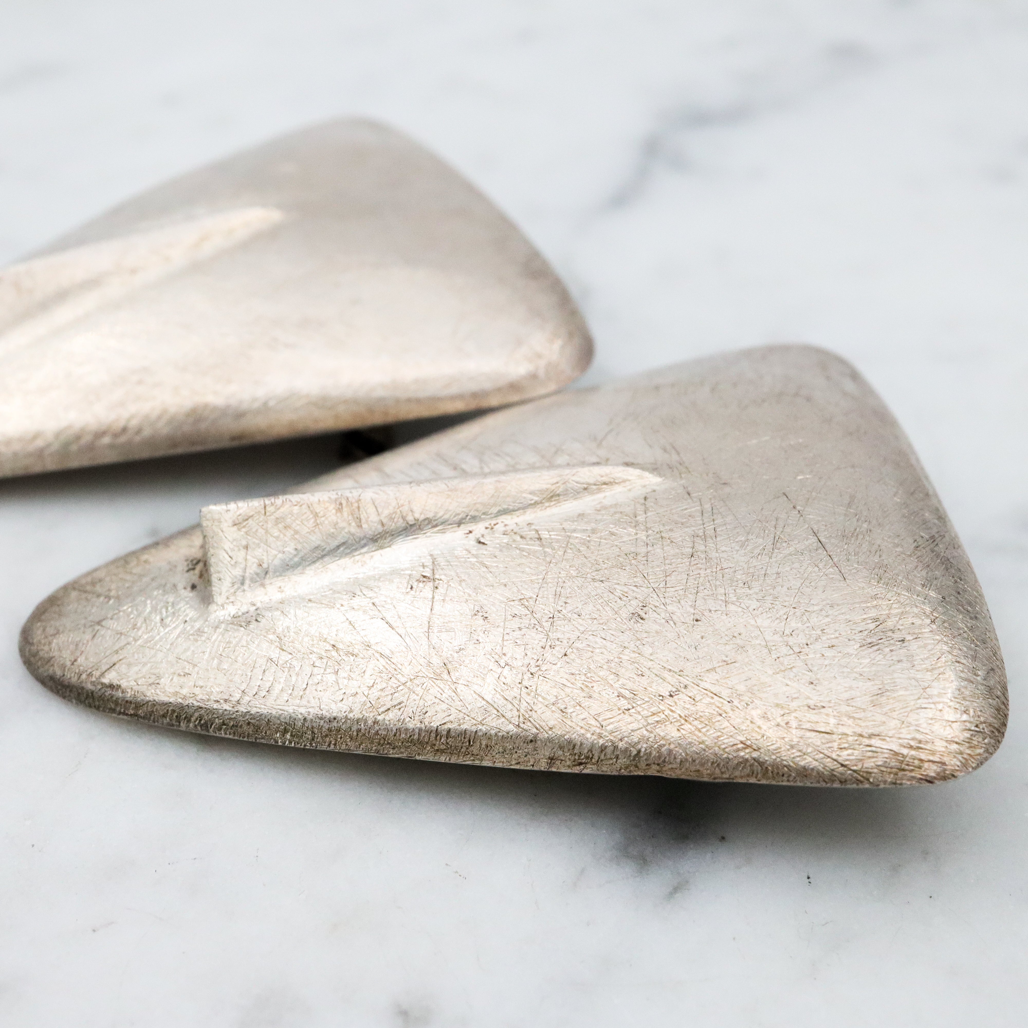1987 pair of brushed sterling mask brooches by Modernist artist Elizabeth Earle